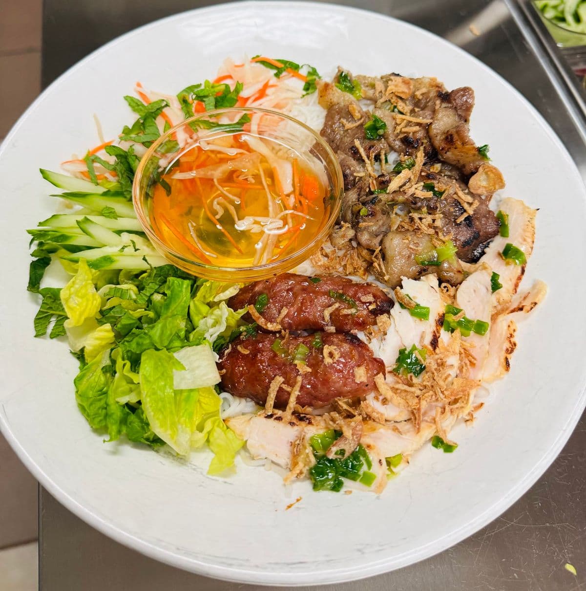 A vermicelli plate with grilled meats, salad and fish sauce.